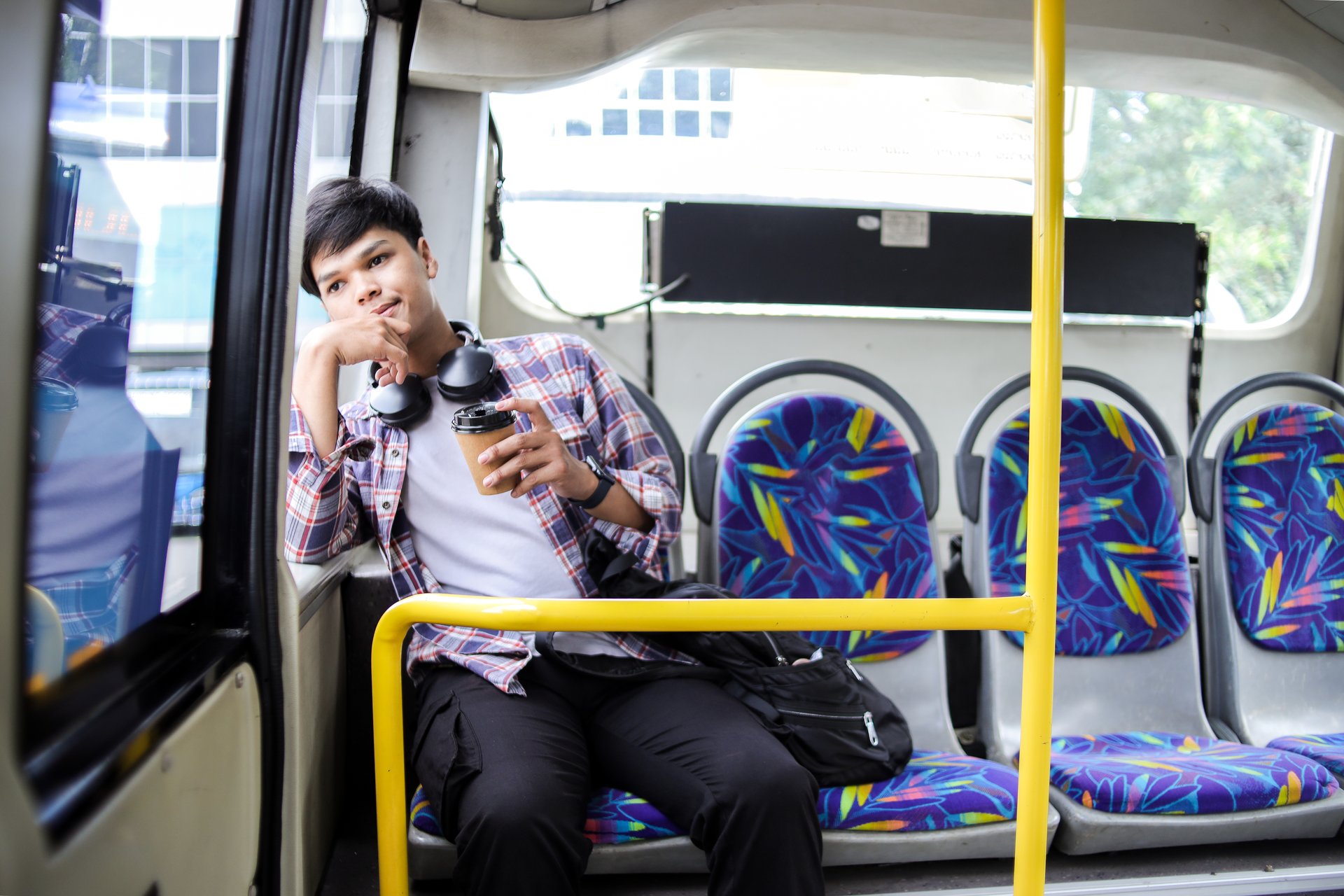 Student z kubkiem kawy siedzi w miejskim autobusie