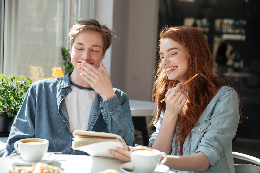 Student i studentka śmieją się przy kawie w kawiarni