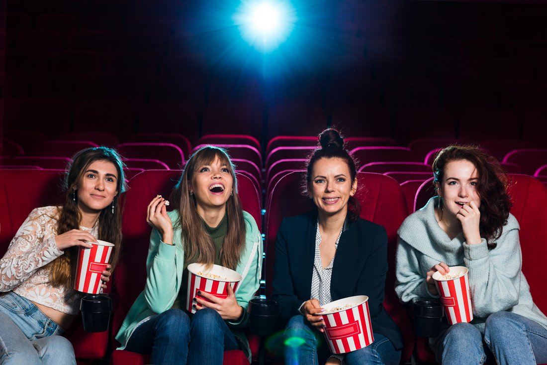 Cztery przyjaciółki z popcornem oglądają film w kinie