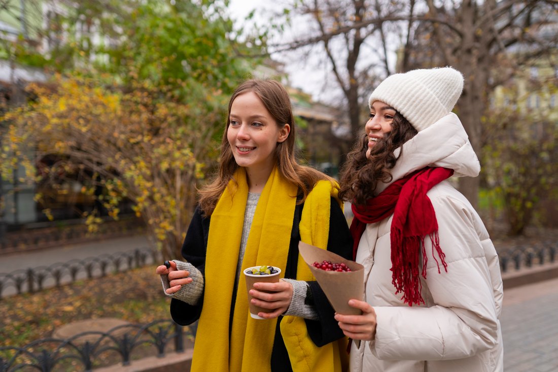 Dwie studentki w szalikach rozmawiają na jesiennym spacerze